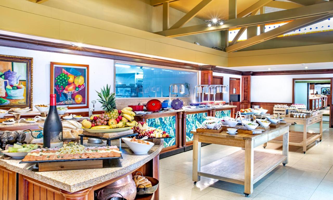 โรงแรมเตเกนดามา โบโกตา ภายนอก รูปภาพ The photo shows a beautifully arranged buffet setup in a restaurant or dining area. There are various food items displayed on tables, including an assortment of fruits such as bananas and grapes, as well as pastries and baked goods. A wine bottle is 