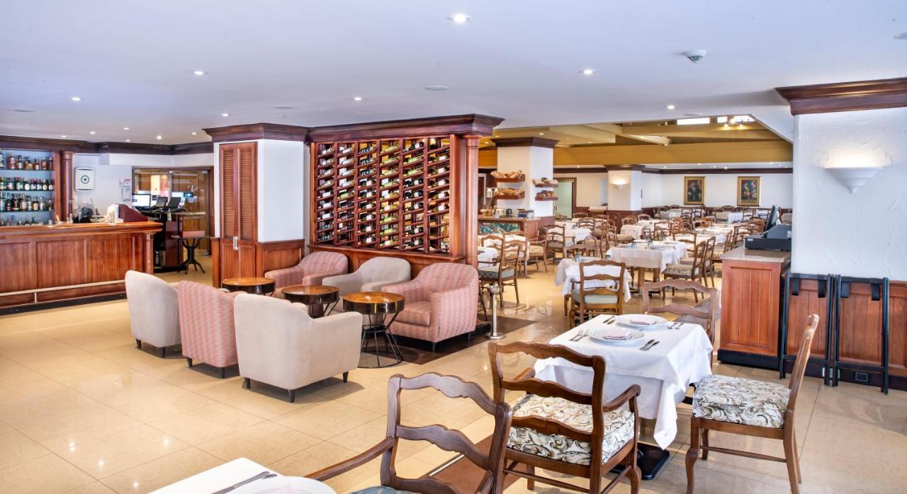 โรงแรมเตเกนดามา โบโกตา ภายนอก รูปภาพ The photo shows the interior of a restaurant. It features a spacious dining area with various tables and chairs arranged throughout. Some tables are set with white tablecloths, indicating a formal dining setup. In one section, there are cozy armchair