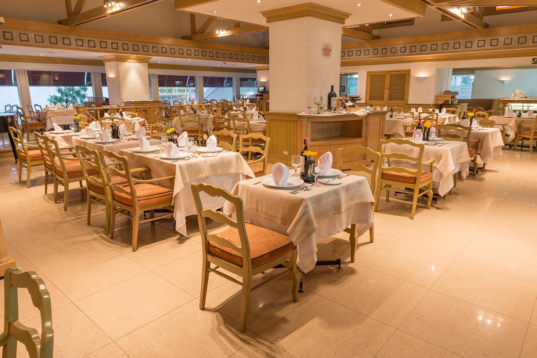 โรงแรมเตเกนดามา โบโกตา ภายนอก รูปภาพ The photo depicts a dining area of a restaurant. The space is furnished with multiple tables, each set with tablecloths and arranged neatly. The chairs are wooden with padded seating, and there are plates, napkins, and utensils prepared for diners. T