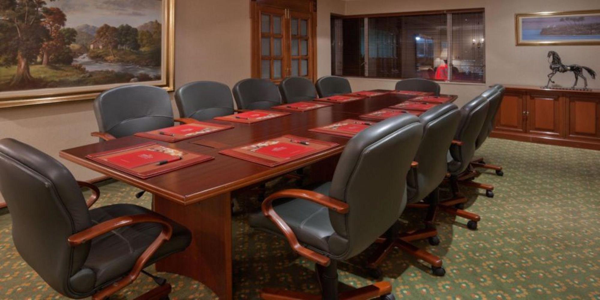 โรงแรมเตเกนดามา โบโกตา สิ่งอำนวยความสะดวก รูปภาพ The photo shows a conference room featuring a large wooden table with several leather office chairs arranged around it. The table is set with red placemats and possibly some materials or documents. In the background, there is a large window that prov